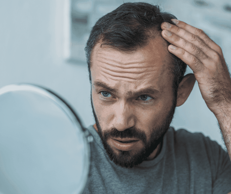 Man inspecting his hairline in the mirror with concern.
