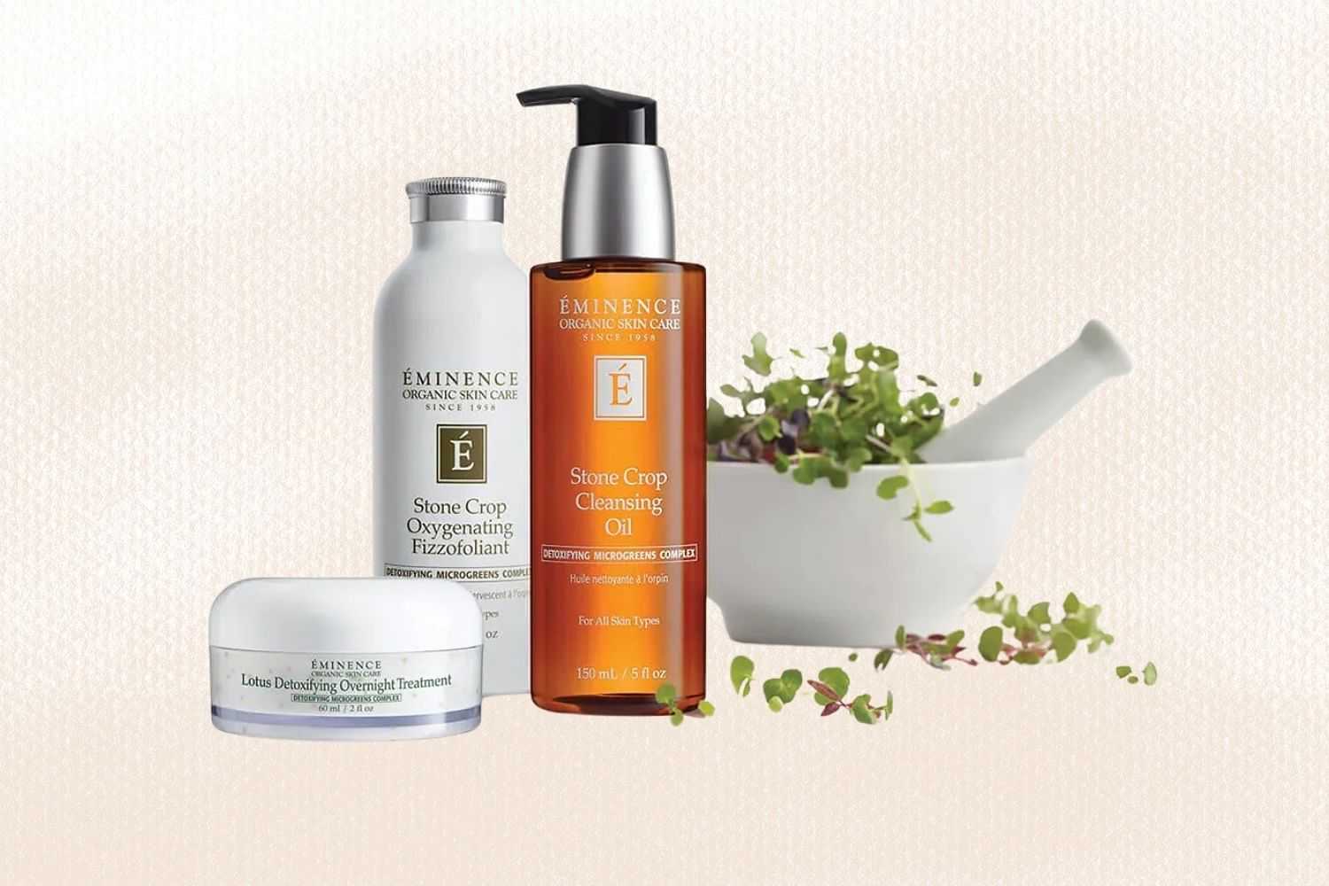 Éminence skin care products displayed with a mortar and pestle filled with fresh green herbs.