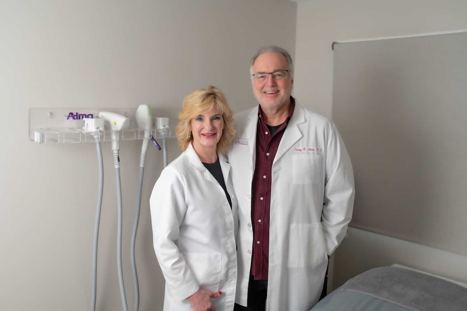 Two smiling doctors in white coats standing in a clinic.